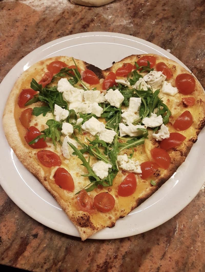 Pizza in Herzform mit Kirschtomaten, Rucola und Mozzarella