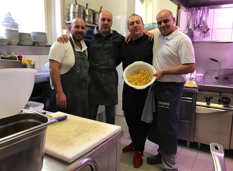 Das Küchenteam des Il Pomodoro mit einem Sieb frisch gekochter Pasta